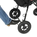 Person’s foot pressing the stroller’s foot brake near the front wheel, demonstrating how to lock the stroller in place.