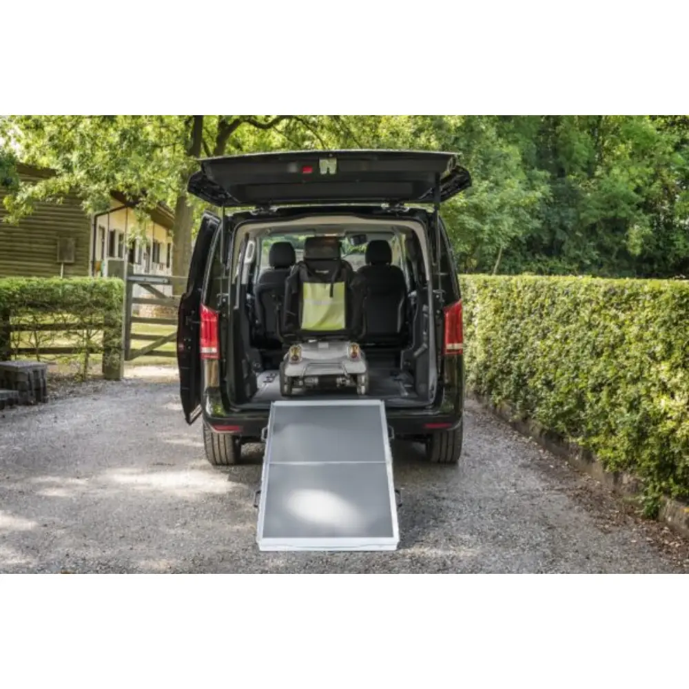 Aerolight Broadfold 2 - O Neill Healthcare Rear view of a black van with its ramp extended for a wheelchair, a mobility chair inside the cargo area.