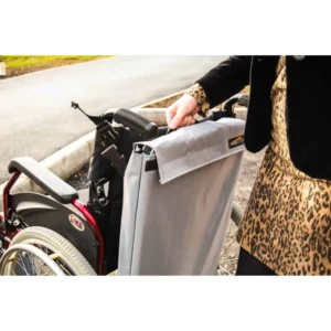 Person in a leopard-print outfit handles a gray foldable ramp attached to a wheelchair for easy accessibility.