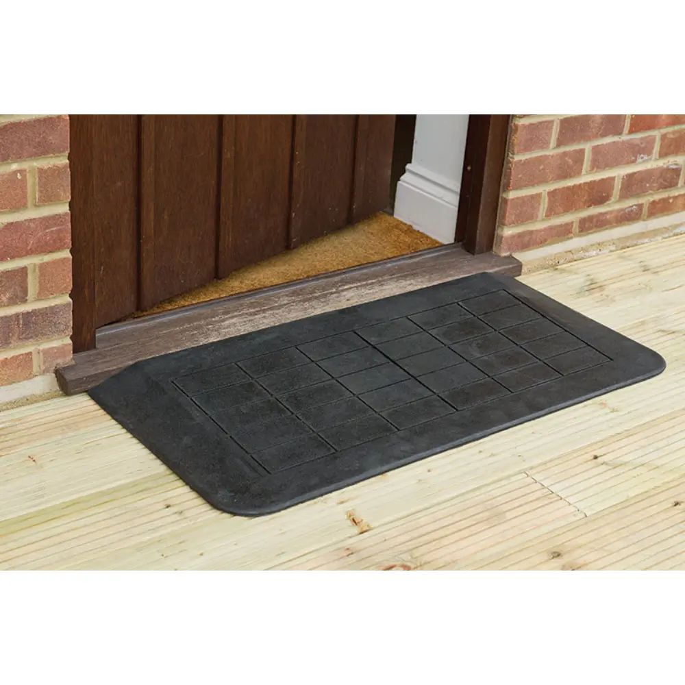 Doorline Neatedge3 - O Neill Healthcare Black rubber entrance mat with a grid pattern in front of a wooden door on a brick house.