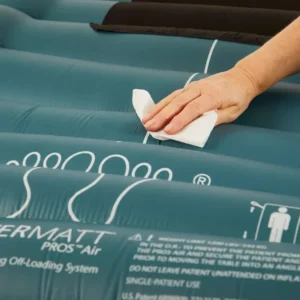 Person’s hand wiping a teal inflatable raft surface with a white cloth.